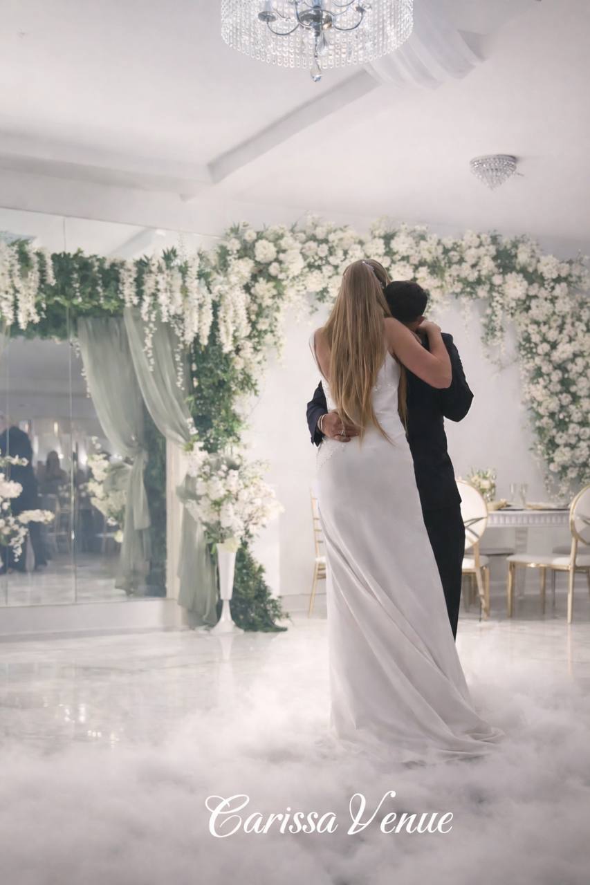 Bride and groom first dance at Carissa Venue with floral arch and fog